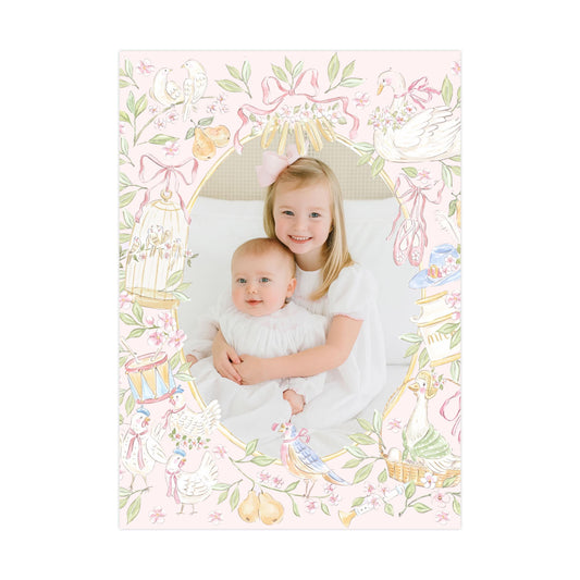 A young girl is holding a baby in a pink and white floral frame, surrounded by various decorative elements such as birds, flowers, and other whimsical illustrations.