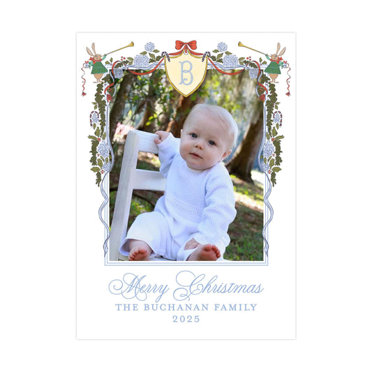A baby sitting in a chair, surrounded by a decorative border with a letter "B" and festive elements such as flowers and a horn. The text below the image reads "Merry Christmas" and "The Buchanan Family" along with the year "2025".
