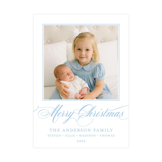 A young girl in a blue dress is holding a sleeping baby in her arms, with the text "Merry Christmas" and "The Anderson Family" written below the image.