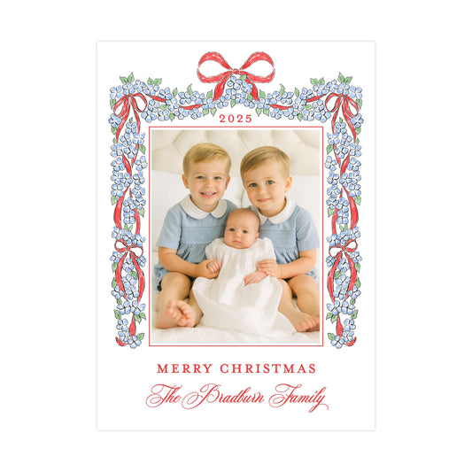 A family portrait of two young boys and a baby, framed by a decorative border with a floral pattern and red ribbons. The text at the bottom of the image reads "Merry Christmas The Bradtun Family".