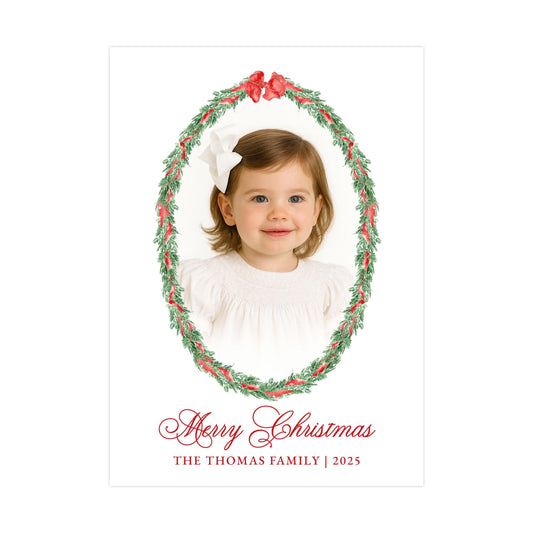 A young girl with a white bow in her hair is the central focus of the image, surrounded by a festive wreath. The text "Merry Christmas" is displayed at the bottom of the image, and "THE THOMAS FAMILY | 2025" is written at the bottom right corner.