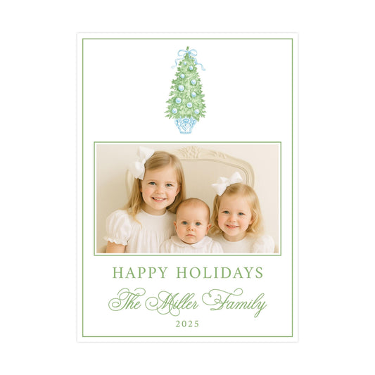 A family portrait of three young girls, likely sisters, with a Christmas tree in the background. The text below the image reads "Happy Holidays The Miller Family 2020".