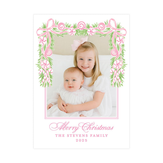 A young girl and a baby are sitting together in a frame with a floral border, surrounded by a decorative border of pink and green leaves. The text at the bottom of the image reads "Merry Christmas THE STEVENS FAMILY 2015".