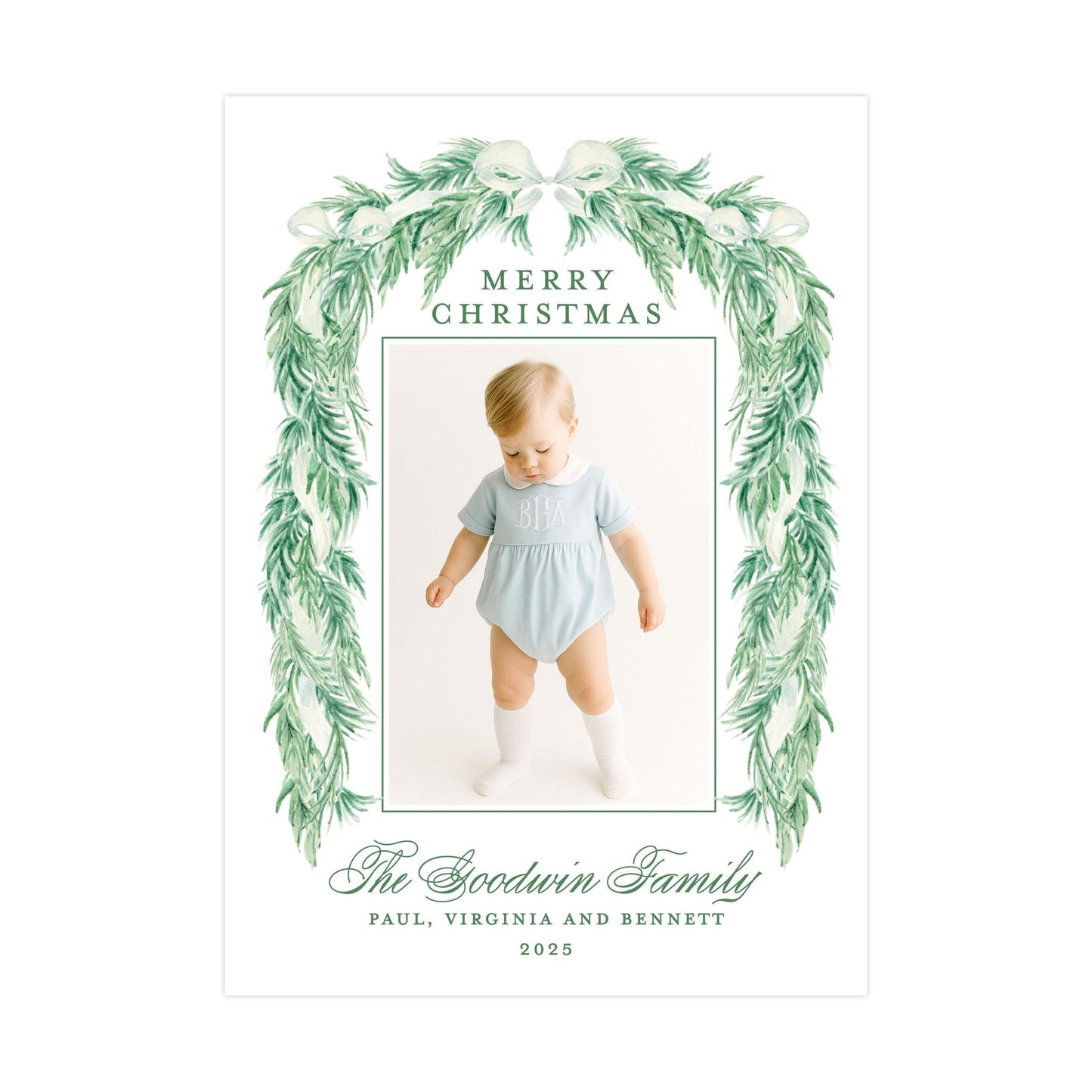 The image is a Christmas card featuring a baby wearing a light blue outfit, surrounded by a green wreath. The card has a message that reads "Merry Christmas" and includes the names "Paul, Virginia and Bennett" along with the year "2025".