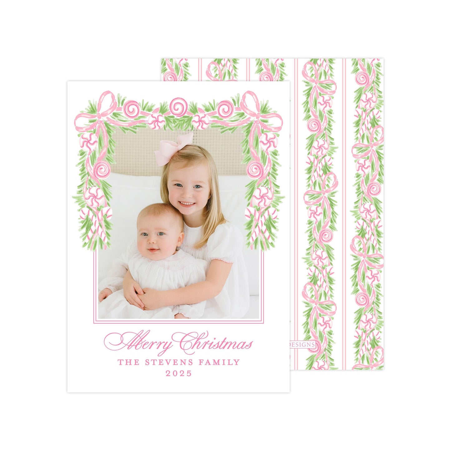 A young girl is holding a baby in a white dress, both smiling and posing for a photograph. The image is framed by a decorative border with pink and green floral elements. The text at the bottom of the image reads "A merry Christmas THE STEVENS FAMILY 2015".