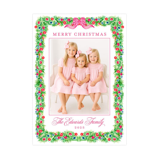 A family photo of three young girls in pink dresses, with a festive Christmas wreath border surrounding the image.