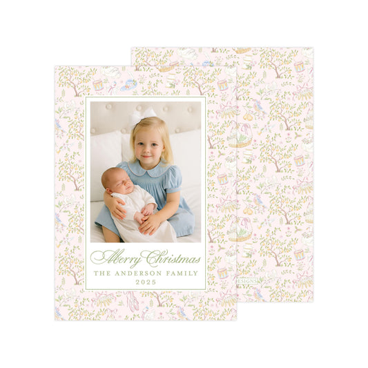 A young girl is holding a baby in a cozy setting, surrounded by a floral pattern. The text on the card reads "Merry Christmas" and "The Anderson Family" along with the year "2025".