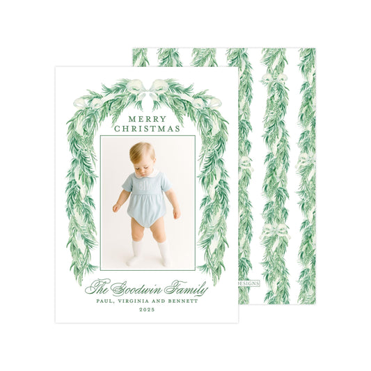 A Christmas card featuring a baby wearing a light blue outfit, surrounded by a green wreath and text that reads "Merry Christmas" and "The Sweetness Family Paul, Virginia and Bennett 2005".