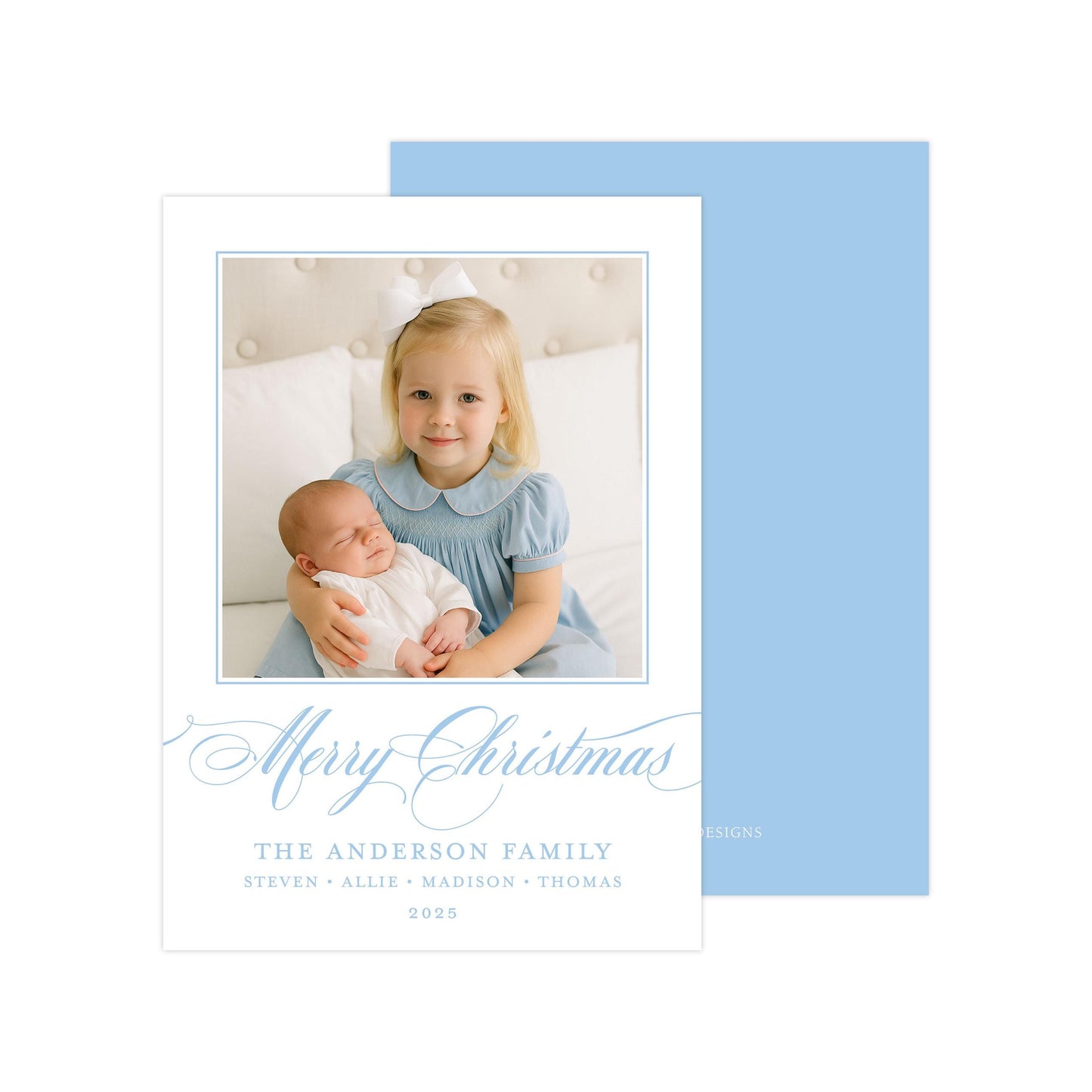 A young girl in a blue dress is holding a sleeping baby in her arms, with a "Merry Christmas" message and the name "The Anderson Family" written below.