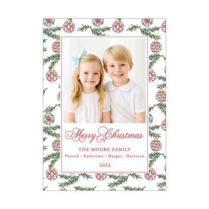 A Christmas-themed photo frame with two children, a girl and a boy, smiling and posing together. The frame has a border with a pattern of Christmas ornaments and greenery. The text on the frame reads &quot;Merry Christmas&quot; and &quot;The Moore Family&quot; along with the year &quot;2025&quot;.