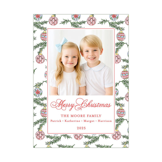A Christmas-themed photo frame with two children, a girl and a boy, smiling and posing together. The frame has a border with a pattern of Christmas ornaments and greenery. The text on the frame reads &quot;Merry Christmas&quot; and &quot;The Moore Family&quot; along with the year &quot;2025&quot;.