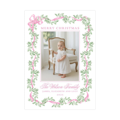 A framed photograph of a baby girl in a white dress, standing in a chair with a floral border around the edges. The text &quot;Merry Christmas&quot; is displayed above the photo, and &quot;The Wilson Family&quot; is written below it.