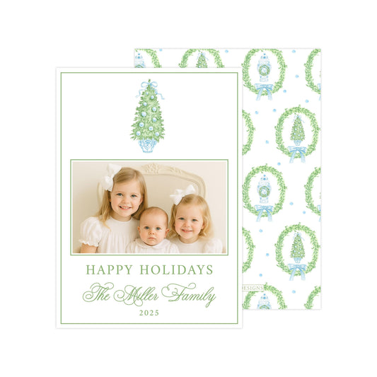 A family photo of three young girls, likely sisters, smiling and posing together. The photo is framed by a wreath pattern and the text &quot;Happy Holidays The Miller Family 2015&quot;.