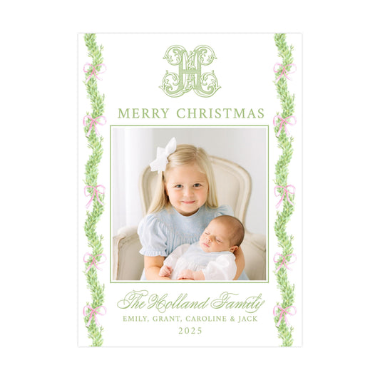 a young girl holding a sleeping baby, with a decorative border of greenery and pink ribbons around the edges. The text at the top reads &quot;MERRY CHRISTMAS&quot; and the text at the bottom reads &quot;The Kolland Family&quot;.