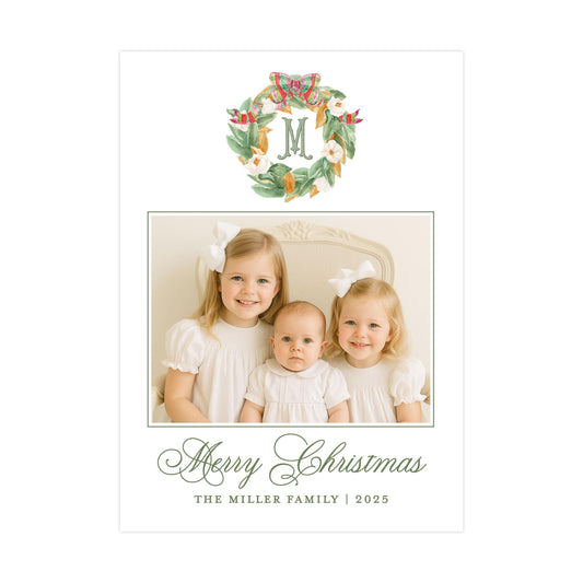 A family photo of three young girls, likely sisters, posing together for a Christmas card. The card has a wreath design and a message wishing the recipient a Merry Christmas.