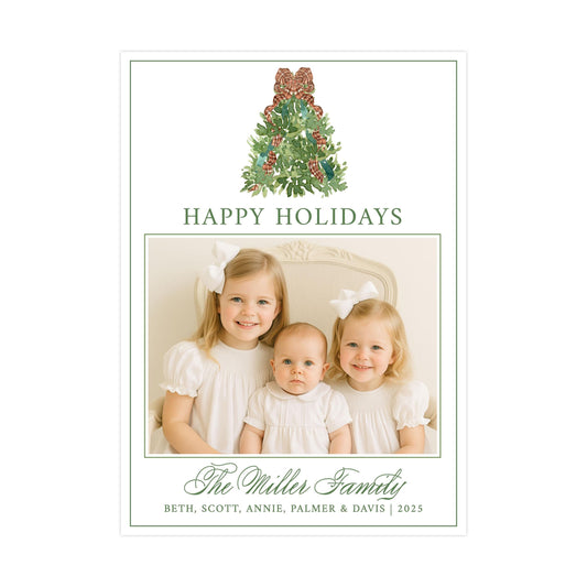 A family portrait of three young girls, likely sisters, with a Christmas tree in the background. The text &quot;HAPPY HOLIDAYS&quot; is displayed above the photo, and &quot;The Miller Family&quot; is written below the photo.