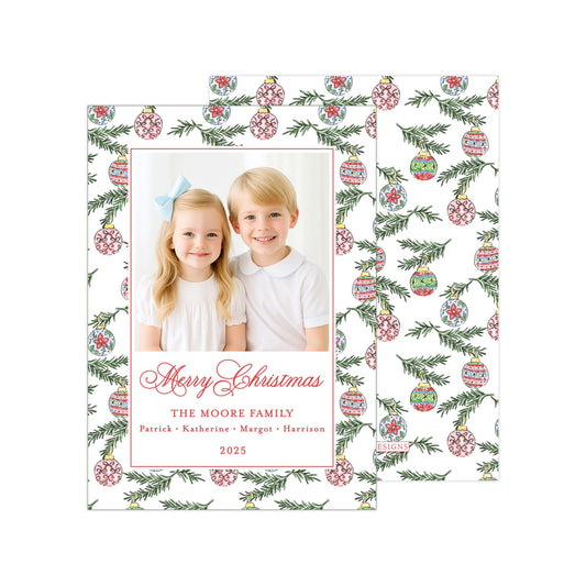 A Christmas card featuring two children, a girl and a boy, smiling and posing together in front of a patterned background with Christmas ornaments.