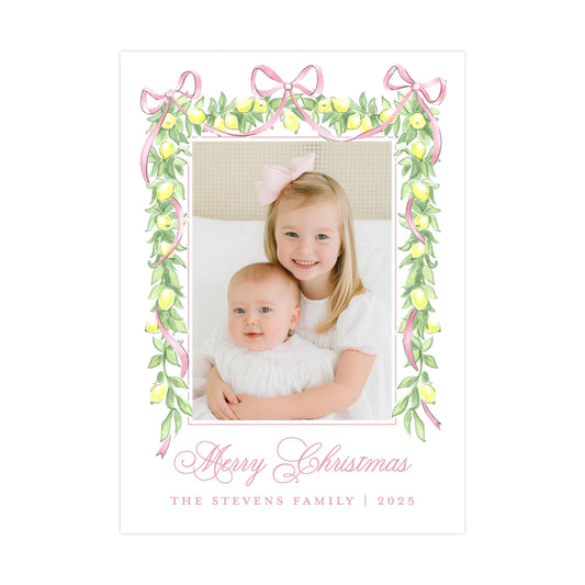 A young girl and a baby are sitting together in a frame, surrounded by a decorative border of lemons and pink ribbons. The text &quot;Merry Christmas&quot; is written in a cursive font at the bottom of the image.