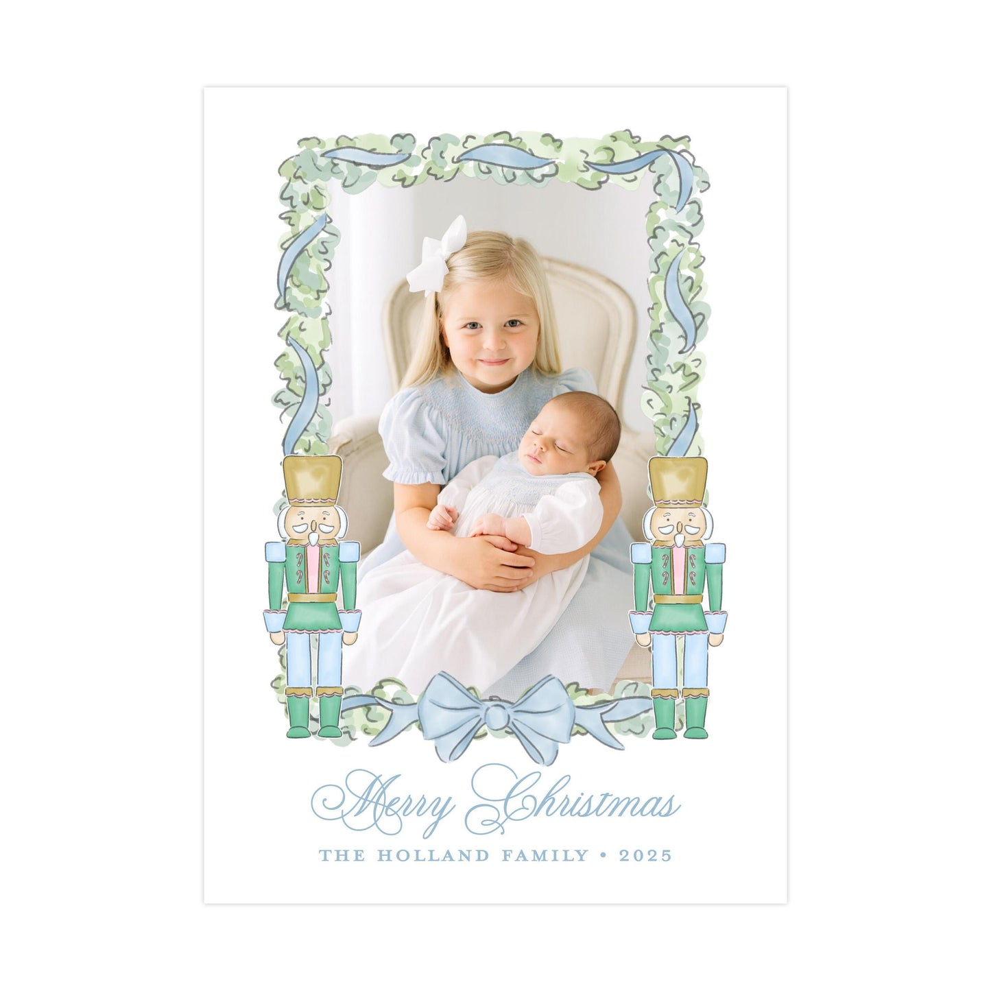 A young girl is holding a baby in her arms, with a nutcracker figure on either side of the frame. The image is framed with a decorative border and the text &quot;Merry Christmas&quot; and &quot;The Holland Family&quot; is displayed below.