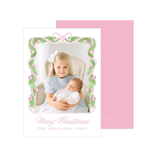A young girl is holding a sleeping baby in her arms, with a pink and white floral frame surrounding the image. The text "Merry Christmas" and "THE HOLLANDS | 2025" is displayed below the image.