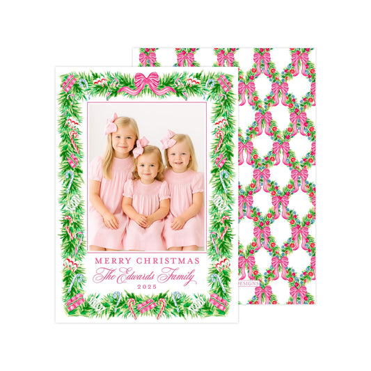 A Christmas card featuring three young girls in pink dresses, with a festive floral border and a personalized message.