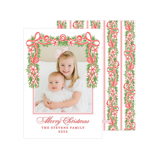 A Christmas card featuring two young girls, one wearing a white dress and the other in a white outfit, with a festive border of red and green ribbons and greenery. The card has a personalized message and year, and the image is described as a collage of multiple images.